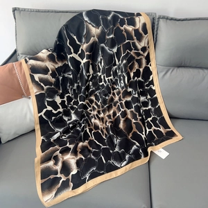 Detailed view of the silk-like abstract giraffe print texture on this elegant brown scarf