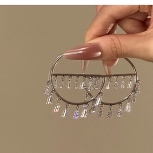 Detail of silver drop earrings with rectangular zircon tassels held by hand