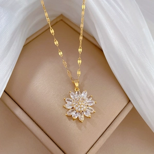 Elegant gold titanium sunflower necklace with sparkling crystals on beige silk background