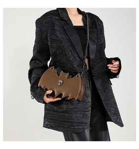 Close-up of brown bat-shaped leather crossbody bag with skull ornament and chain strap