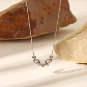 Detail of silver stainless steel necklace with round beads and starfish pebble pendants