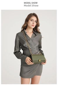 Detail showing deep green quilted crossbody bag with gold chain strap on grey dress