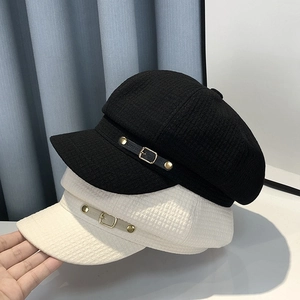 Detail of tweed newsboy caps in black and white with leather straps and metal buckles