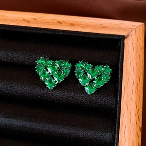 Macro shot of heart-shaped earrings featuring green cubic zirconia on black velvet background