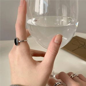 Close-up of vintage 925 silver rings with black agate worn by a model holding glass