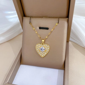 Close-up of gold heart necklace with white zircons in a champagne jewelry box