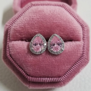 Macro shot of silver pear-cut pink zircon stud earrings in a pink velvet jewelry box