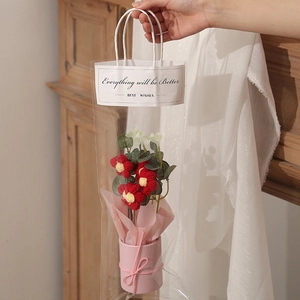 Detail of hand-knitted red flower bouquet in pink pot within a clear gift bag