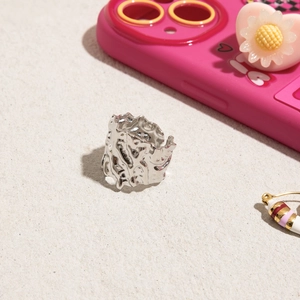 Close-up of silver stainless steel ring with lava texture on light grainy base
