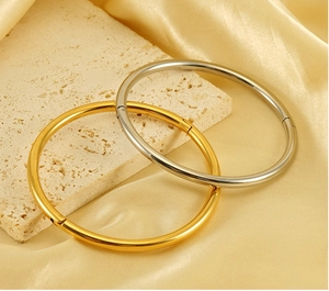 Detailed close-up of gold and silver polished stainless steel hinged bangles on stones