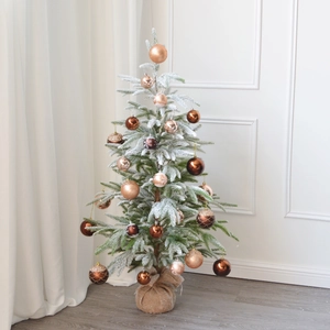 Detail of flocked mini Christmas tree with bronze ornaments and a burlap-wrapped base