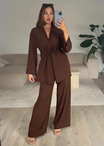 Detail of dark brown long sleeve drawstring top and wide-leg pants with textured fabric