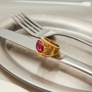 Close-up of a wide gold ring featuring a large square-cut pink zircon on a silver knife