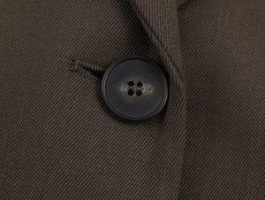 Macro shot of black resin button and sewing detail on brown twill blazer suit set