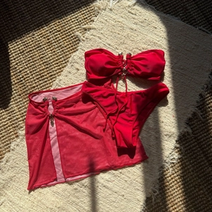 Détail d'un bikini rouge trois pièces avec jupe en résille et breloques cœur dorées