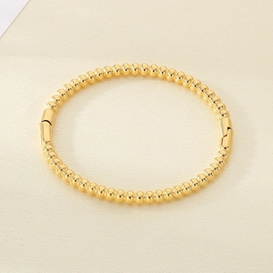 Detail view of the 18K gold-plated beaded bangle featuring a side clasp and polished finish