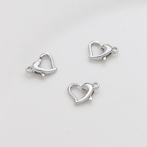 Macro detail of three silver heart-shaped lobster clasps for jewelry making connections