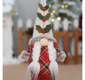 Detail of female Christmas gnome in red plaid dress with white braids and holly berry hat