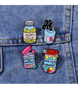 Detail of four enamel medicine pins with quotes on blue denim fabric background