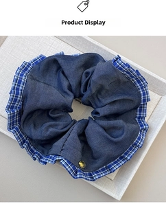 Detail of blue denim scrunchie with plaid ruffle edge and gold metal button decoration