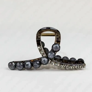 Close-up of small green hair claw clip with faux pearls and rhinestones on gold spring