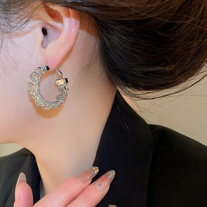 Macro shot of silver woven mesh hoop earrings on model highlighting intricate texture