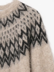 Close-up of beige knit sweater with black geometric jacquard and fuzzy texture