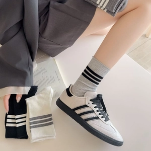 Mid-calf college style striped socks paired with retro cream sneakers for a trendy look