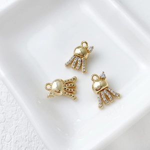 Detailed view of three 14k gold octopus charms with sparkling zircon stones in a tray
