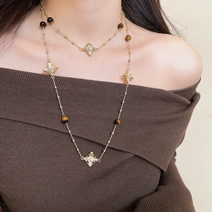 Detailed view of vintage gold layered necklace with tiger eye beads and cross charms