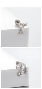 Close-up of titanium steel cartilage earrings with bow, wings, and zircon accents