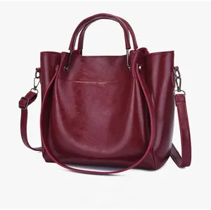 Detail view of burgundy tote bag with glossy synthetic leather and dual handles