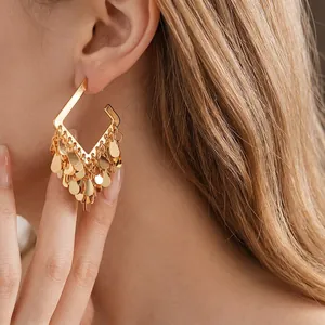 Orecchini a nappa con goccia d'acqua placcati in oro indossati da una modella di lato
