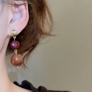 Elegant three-tier drop earrings with gold metal studs and marble resin beads