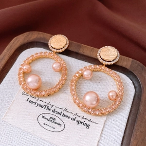 Macro shot of 18K gold plated pearl hoop earrings with zircon pavé and Triomphe logo