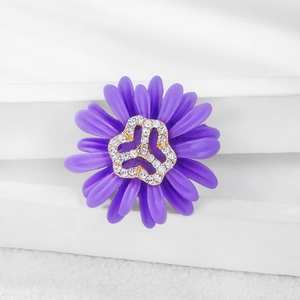 Detailed close-up of purple daisy brooch with white rhinestones on white geometric stand