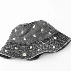 Close-up of small daisy embroidery and parallel stitching on grey washed denim bucket hat