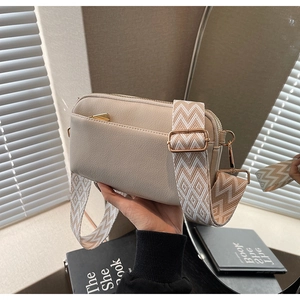 Detail of beige PU crossbody bag with diamond-pattern wide strap and golden hardware