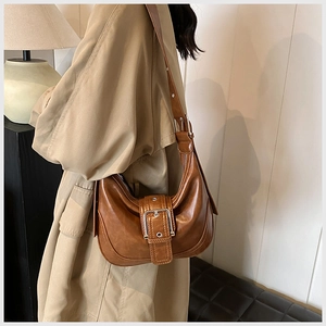 Detailaufnahme der karamellfarbenen Ledertasche mit Silberschnalle zum khakifarbenen Mantel