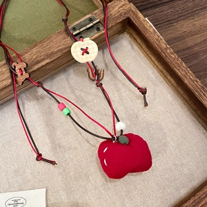 Close-up of handmade necklace with red velvet apple, wooden puppy, and colorful beads
