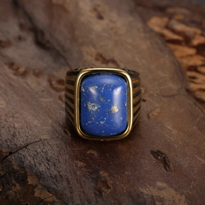 Macro view of vintage gold-tone signet ring with square blue gemstone and striped texture