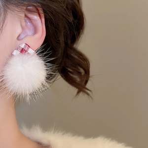 Detailed view of white plush pompom earrings with red and white plaid bow decoration
