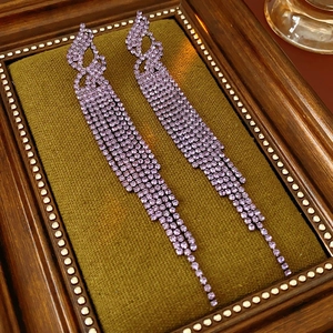 Détail macro de boucles d'oreilles longues à pampilles violettes en strass brillants