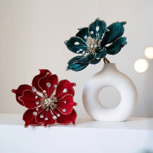 Red velvet magnolia Christmas flower with gold glitter edges in a white ceramic vase