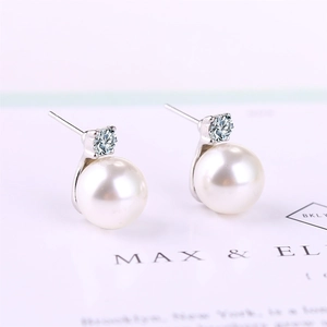 Macro detail of elegant pearl earrings with sparkling zircon studs and silver finish