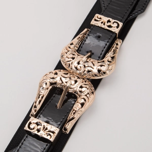 Macro shot of dual vintage gold buckles with intricate floral engravings on a black belt