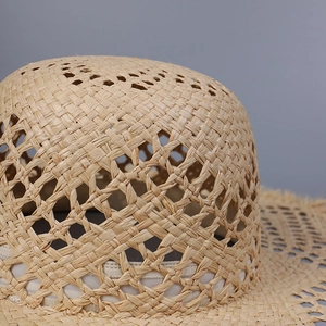 Macro detail of hand-woven raffia straw hat showing hollow knit texture and beige fibers