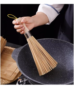 Close-up of a durable bamboo kitchen brush with ergonomic handle used for scrubbing a wok