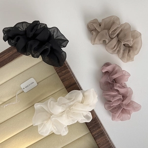 Detail of soft organza hair ties in black, beige, and pink colors on a wooden tray