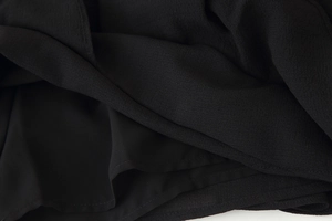 Close-up of black chiffon fabric texture with ruffle layers and neat stitching details
